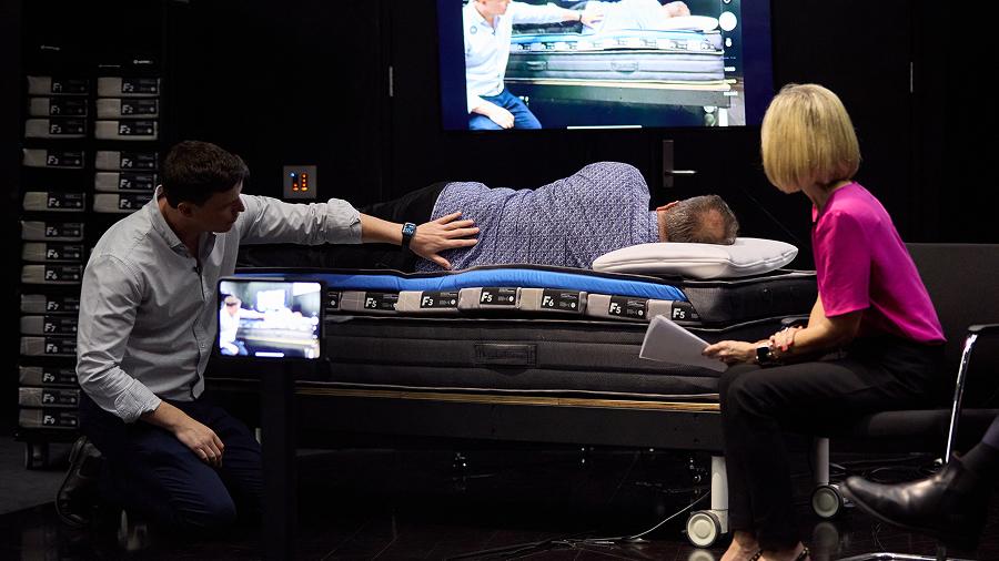 Peter Allen (Physiotherapist) demonstrating a bed fitting with Wayne Johnston and Sophie Scott (Presenter)
